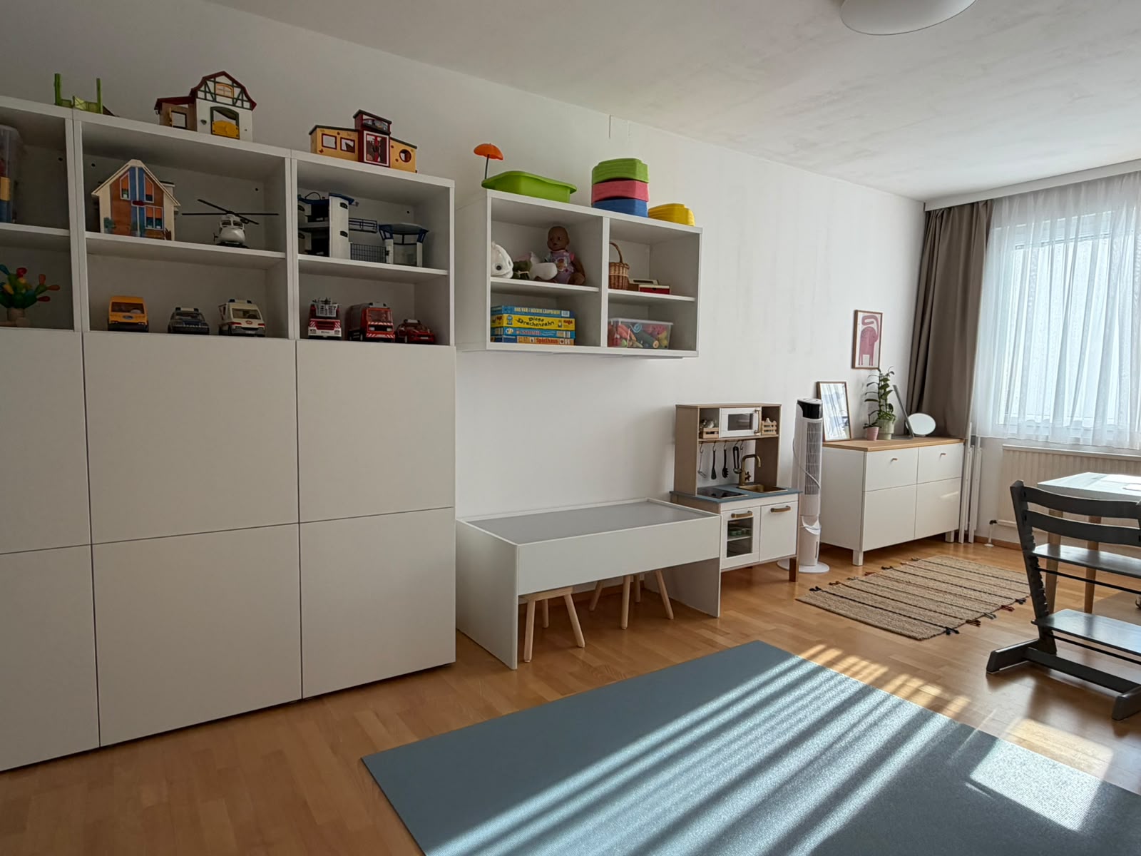 Lichtdurchfluteter Therapieraum mit Spielmaterialien, Kinderküche und großem Fenster
